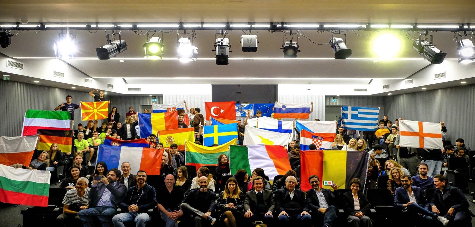 Large multinational group of participants with their national flags in the auditorium on certificate day