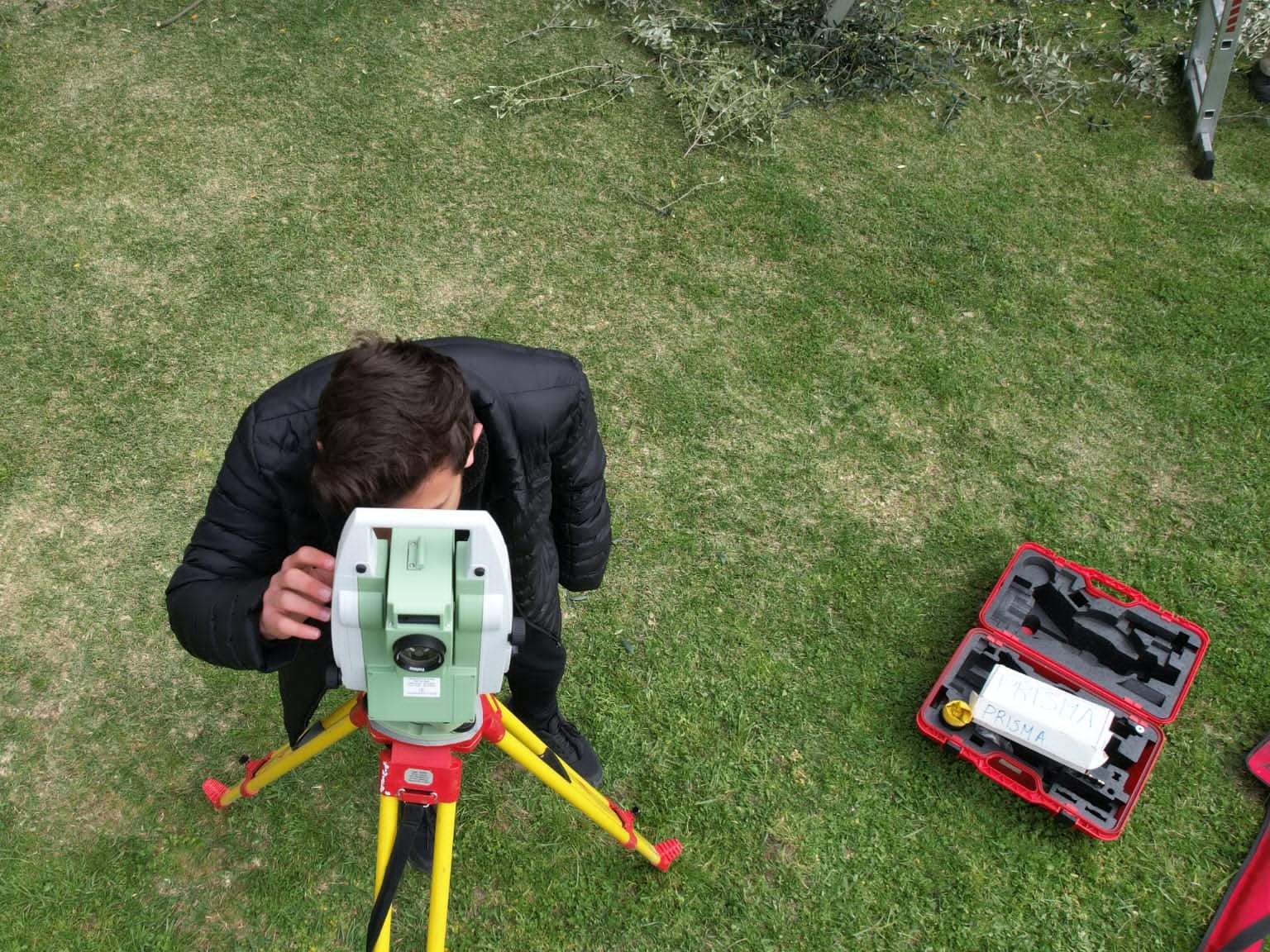 Trainee looking through a total station on a tripod, seen from above