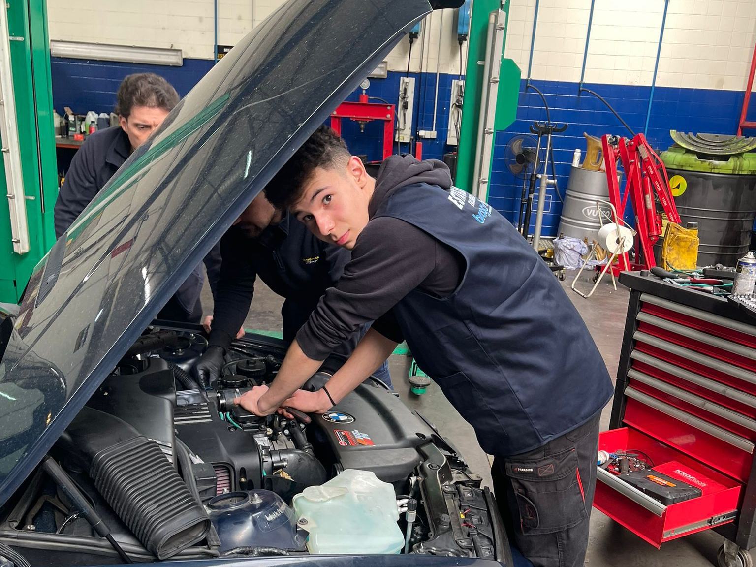 Car mechanics trainees working on an engine in a garage