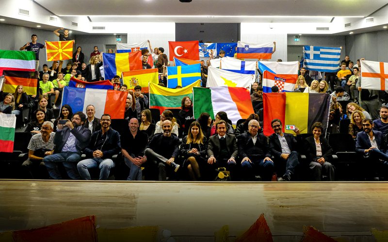 Auditorium full of participants holding the flags of their countries