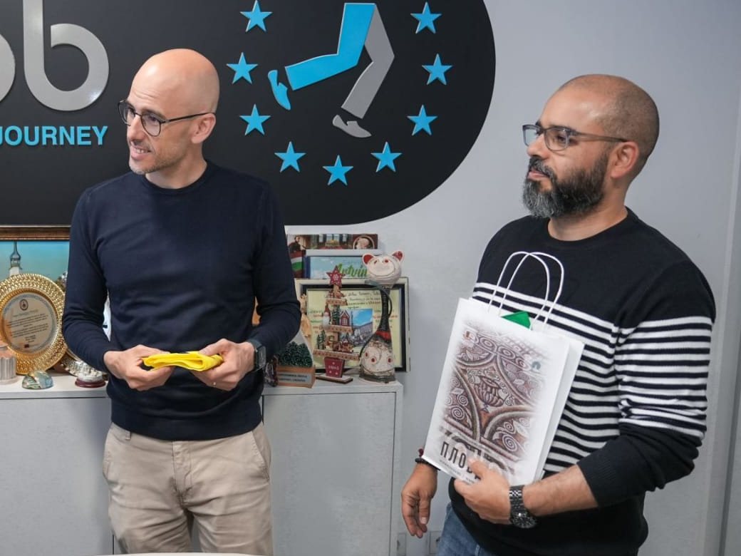 Two members of the BragaMob team in the office, in front of the logo