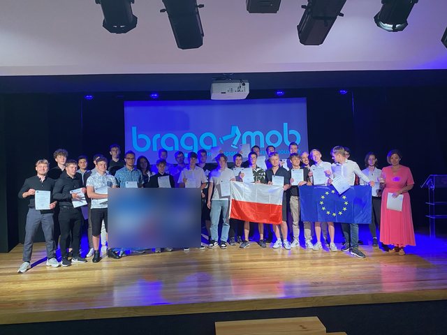 Group with the Polish and European flags on stage with their certificates