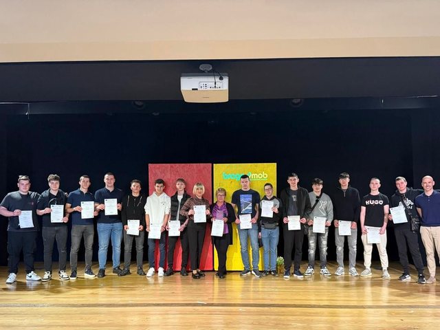 Group with their certificates on the auditorium stage