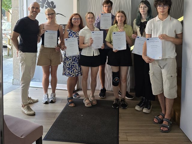 Group with their certificates at the entrance of a restaurant