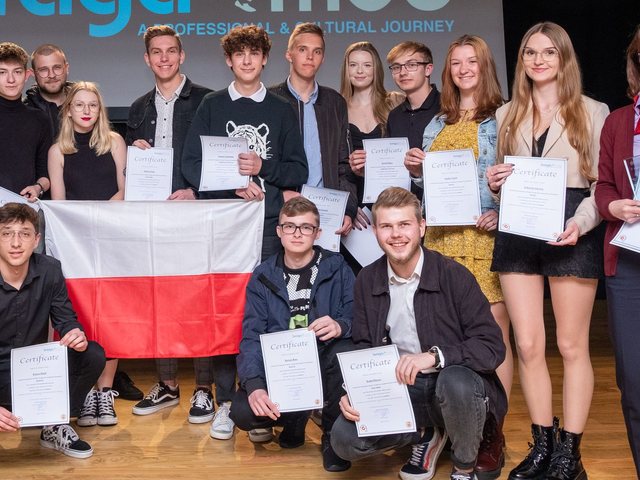 Group with the Polish flag and their certificates on stage